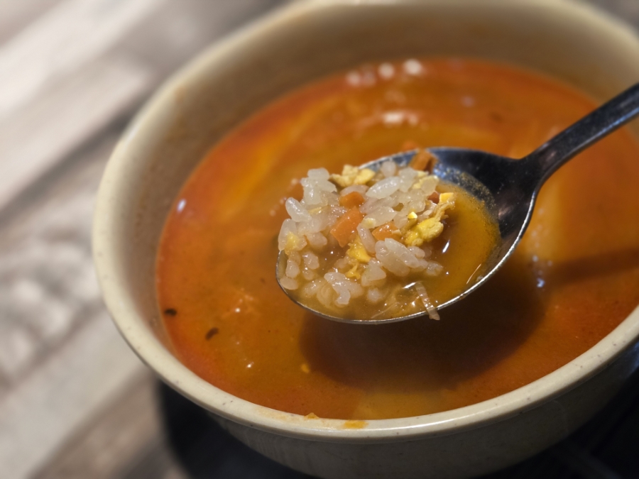 A spoonful of Korean fried rice dipped into spicy jjambbong soup