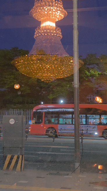 A Korean neighborhood street seen through a window on a May evening