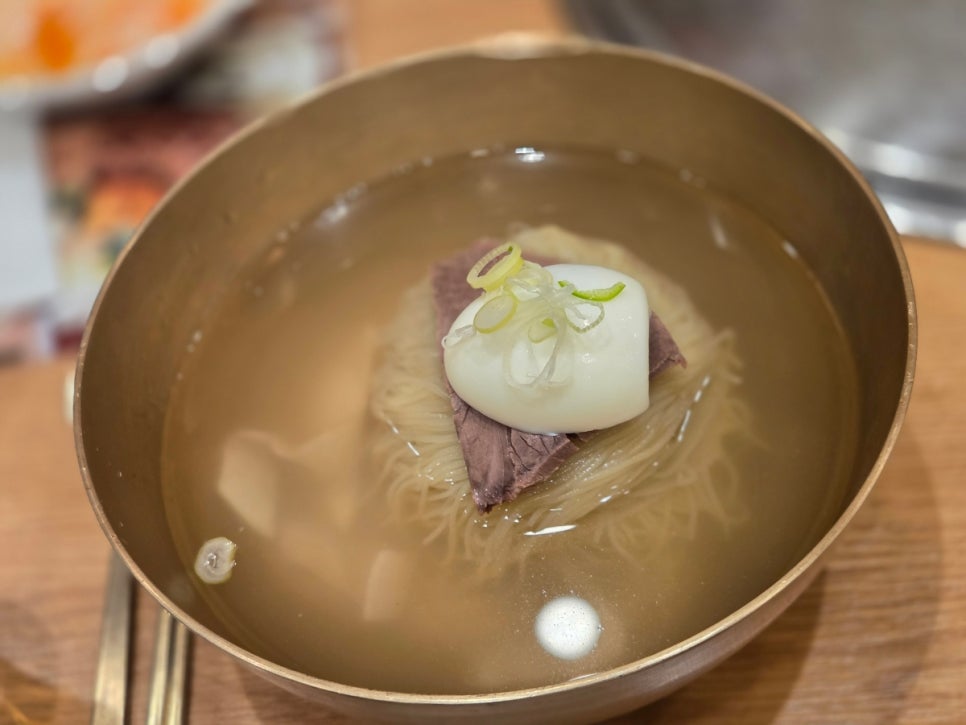 A bowl of Pyeongyang naengmyeon with cold broth and thin noodles